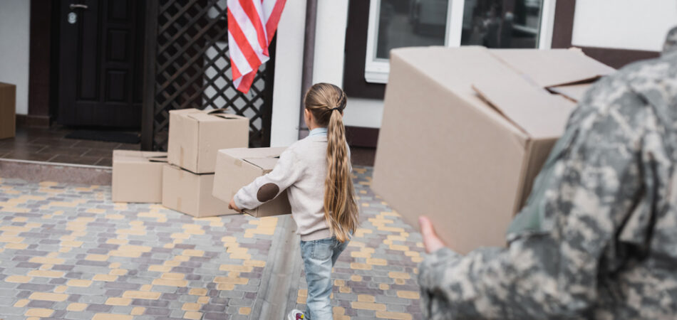 Back,view,of,girl,carrying,cardboard,box,near,house,with