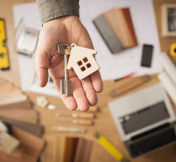 Real,estate,agent,handing,over,a,house,key,,desktop,with