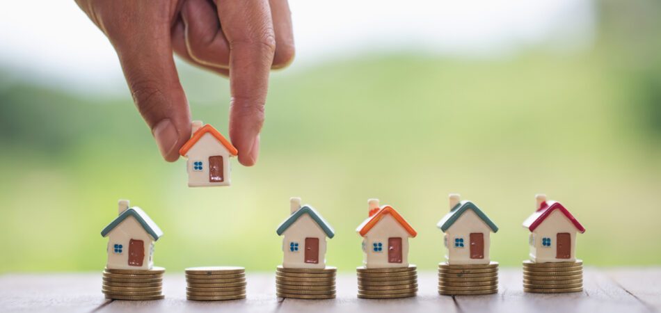 Woman's,hand,putting,house,model,on,coins,stack.,concept,for